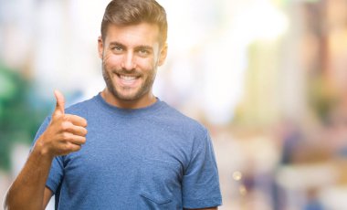 Yakışıklı delikanlı hareketi el ile mutlu yaşasın yapıyor izole arka plan üzerinde. Kameraya bakarak başarı gösteren ile ifade onaylama.