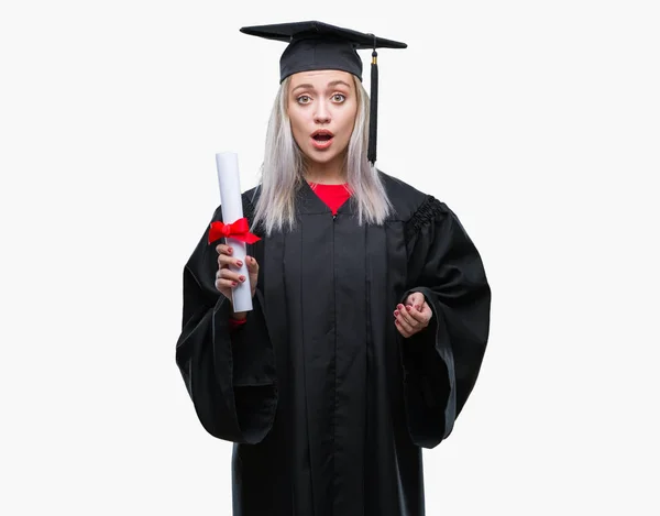 年轻的金发女子穿毕业均匀持有程度在孤立的背景害怕在休克与惊讶的脸 害怕和兴奋与恐惧表达 — 图库照片