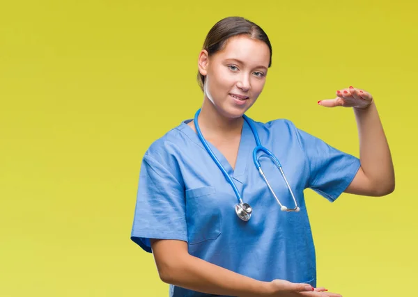 年轻的高加索医生妇女穿着医疗制服在孤立的背景示意与手显示大和大尺寸的标志 措施符号 看着镜头微笑 测量概念 — 图库照片