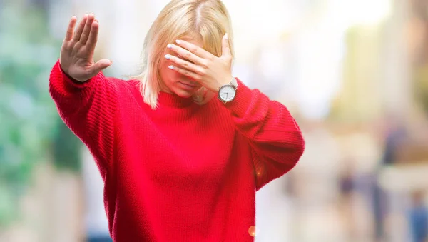 Young beautiful blonde woman wearing sweater and glasses over isolated background covering eyes with hands and doing stop gesture with sad and fear expression. Embarrassed and negative concept.