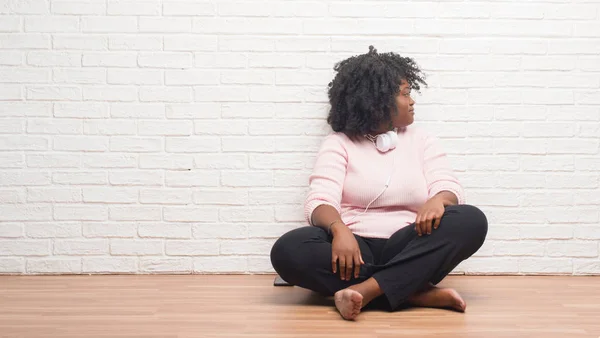 Young African American Woman Sitting Floor Wearing Headphones Looking Side — Stock Photo, Image