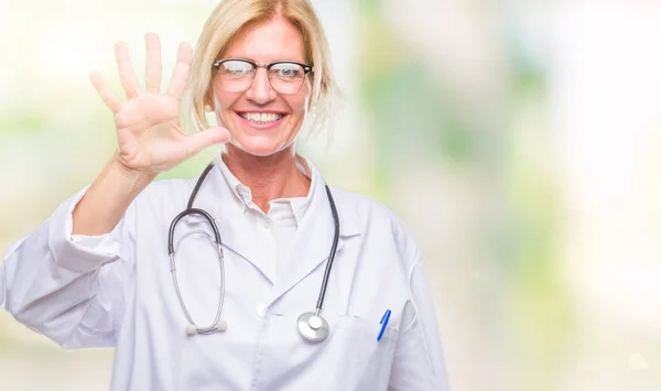 中年金发碧眼的医生妇女在孤立的背景显示和指着手指数字五 同时微笑着自信和快乐 — 图库照片