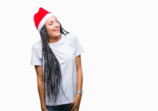 年轻的编织头发非洲裔美国女孩戴着圣诞帽在孤立的背景看着一边面带微笑 自然的表情 笑自信 — 图库照片
