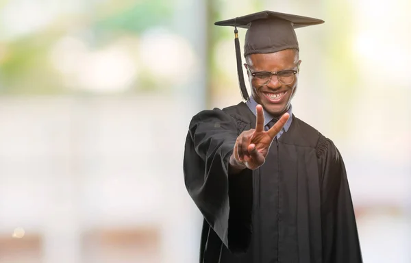 Young graduated african american man over isolated background smiling looking to the camera showing fingers doing victory sign. Number two.