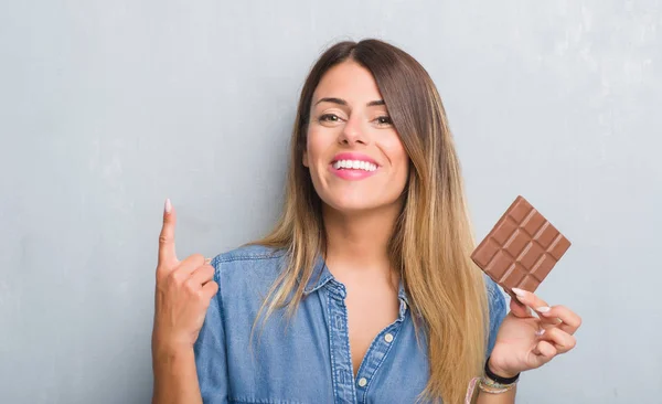 Junge Erwachsene Frau Über Grauer Grunge Wand Beim Schokoriegel Essen — Stockfoto