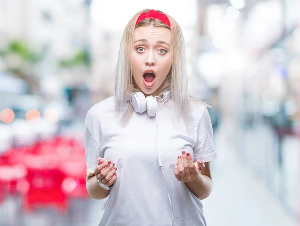 Молодая Блондинка Наушниках Слушающая Музыку Изолированном Фоне Напуганная Потрясенная Неожиданным — стоковое фото