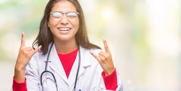 Young arab doctor woman over isolated background shouting with crazy expression doing rock symbol with hands up. Music star. Heavy concept.