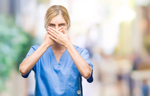 若い美しい金髪の医者の外科医看護師女性ミスのため手で口を覆っているショックを受けて孤立の背景の上 秘密の概念 — ストック写真