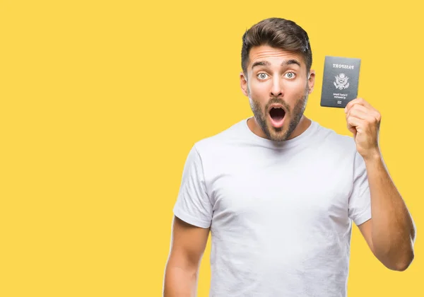 年轻英俊的男子拿着美国的护照在孤立的背景吓得惊讶与一个惊喜的脸 害怕和兴奋与恐惧的表情 — 图库照片
