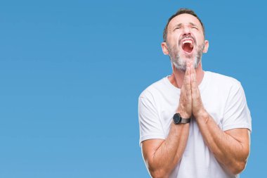 Yalvarıyor ve umut ifade yüzünde çok duygusal ve endişe ile birlikte elleriyle dua izole arka plan üzerinde beyaz t-shirt giyen orta yaş ağarmış komuta sizde. Bağışlanmak. Din kavramı.