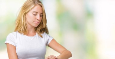 Kol saati, rahat ve kendinden emin zamanında kontrol izole arka plan üzerinde rahat beyaz t-shirt giyen güzel genç kadın