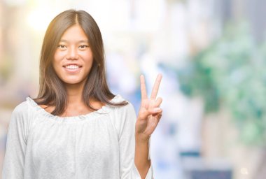 Genç Asyalı kadın gösterilen ve parmakları ile işaret izole arka plan üzerinde ikincisi ise kendinden emin ve mutlu gülümseyerek.