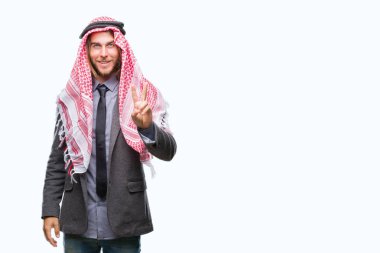 Genç yakışıklı Arap adam uzun saçlı zafer işareti yapıyor parmak gösterilen kamera seyir gülümseyen izole arka plan üzerinde keffiyeh giyiyor. İki numaralı.