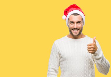 Genç yakışıklı adam hareketi el ile mutlu yaşasın yapıyor izole arka plan üzerinde santa claus şapka giyiyor. Kameraya bakarak başarı gösteren ile ifade onaylama.
