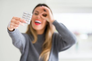 Mutlu yüz el parmaklarının arasından seyir göz üzerinde ok işaretiyle yapıyor gülümseyen ile ilaç ilaçlar evde tutan genç güzel kadın