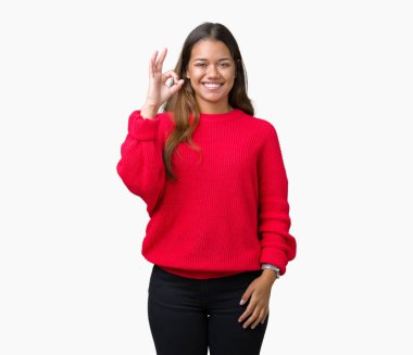 İzole arka plan el ve parmaklar ok işaretiyle yapıyor olumlu gülümseyen üzerinde kırmızı kış kazak giyen genç güzel esmer kadın. Başarılı ifade.