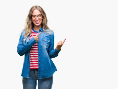 Gülümseyen ve iki elleri ve parmakları ile tarafına işaret kamera bakarak izole arka plan üzerinde gözlük güzel sarışın genç kadın.