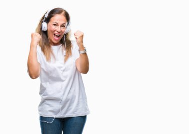 Orta yaş İspanyol kadın üzerinde kulaklık giyen müzik arka plan çok mutlu ve heyecanlı kaldırdı, silah ile kazanan jest yapıyor gülümseyen ve başarı için çığlık izole. Kutlama kavramı.