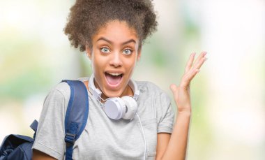 Sırt çantası tutan genç güzel afro Amerikan öğrenci kadın büyük gülümseme ile çığlık zaferini kutluyor ve ellerini kaldırdı arka plan çok mutlu ve heyecanlı, kazanan ifade izole