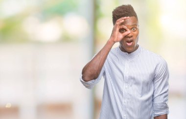 Sürpriz yüz, göz parmaklarının arasından seyir ile ok jest yapıyor izole arka plan üzerinde genç Afro-Amerikan adam şok. İmansız ifade.