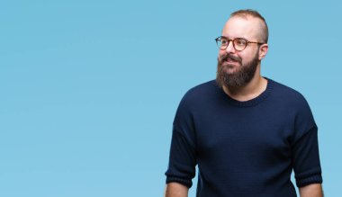 Genç beyaz hipster adam görünümlü yan ve dik dik bakma uzağa düşünce gülümseyen izole arka plan üzerinde güneş gözlüğü takıyor.