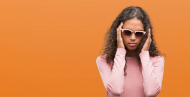 Güzel genç İspanyol kadın giyiyor güneş gözlüğü ile baş ağrısı için kafasına çünkü el stres. Migren muzdarip.