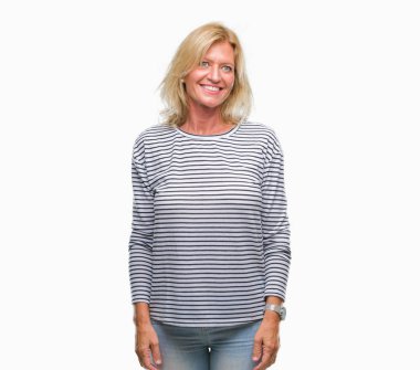 Orta yaş sarışın kadın izole arka plan uzak tarafına gülümseme ile yüzünde, doğal ifade seyir üzerinde. Kendine güvenen gülüyor.