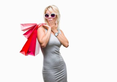 Hata, korku, sessizlik içinde gizli kavramı korkmuş ifade için utanç ile genç güzel sarışın kadın izole arka kapak ağız el ile üzerinden Holding alışveriş torbaları satış alışveriş şok