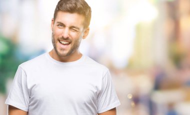 Genç yakışıklı adam seksi bir ifadeyle, neşeli ve mutlu yüzünü kameraya bakarak göz kırpıyor izole arka plan üzerinde.