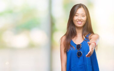 Genç Asyalı kadın dostu sunan el sıkışma tebrik ve davet edici olarak gülümseyen izole arka plan üzerinde. Başarılı iş.