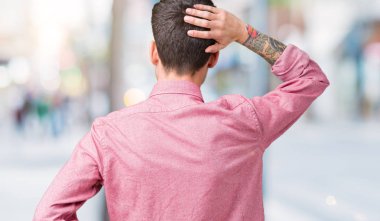 Yakışıklı delikanlı izole arka plan geriye düşünme hakkında şüphe ile baş taraftan üzerinde pembe gömlek giymiş