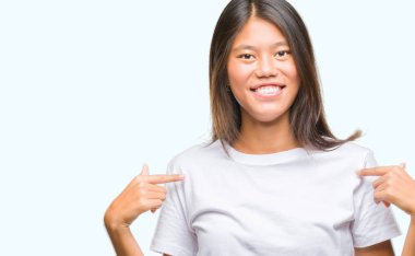 Yüzünde gülümseme ile kendinden emin görünüyorsun, kendini gururlu ve mutlu parmakları ile işaret izole arka plan üzerinde Genç Asyalı kadın.