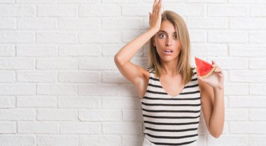 Güzel genç kadın baş, el ile vurguladı su kavun dilimi yemek beyaz tuğla duvarın üzerinden şok utanç ve sürpriz suratla, öfkeli ve sinirli. Korku ve hata için üzgün.