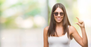 Gülümseyen güneş gözlüğü ve süre seyir ve kamera boyutu işaret parmaklarıyla yapıyor el ile kendinden emin eller genç güzel İspanyol. Ölçü kavramı.