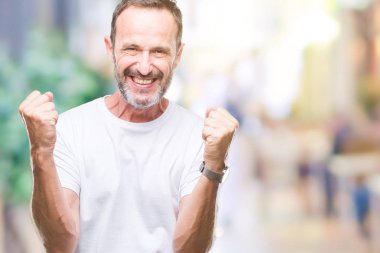 Orta yaş ağarmış komuta sizde izole arka plan kutlama üzerinde beyaz t-shirt giyen şaşırttı ve silah ile başarı için yükseltilmiş ve açık gözler hayrete düşürdü. Kazanan kavramı.