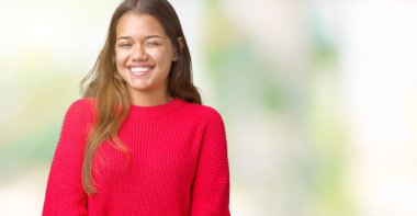 Seksi bir ifadeyle, neşeli ve mutlu yüzünü kameraya bakarak göz kırpıyor izole arka plan üzerinde kırmızı kış kazak giyen genç güzel esmer kadın.