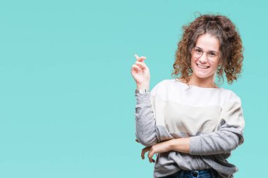 Kameraya bakarak yan el ve parmak ile işaret yüzünde kocaman bir gülümseme ile izole arka plan üzerinde gözlük güzel esmer kıvırcık saçlı Genç kız.