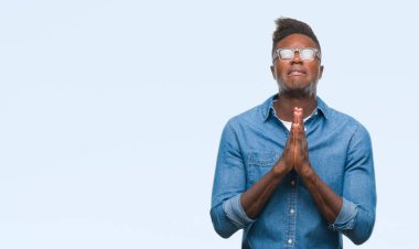 Afrikalı-Amerikalı genç yalvarıyor ve umut ifade yüzünde çok duygusal ve endişe ile birlikte elleriyle dua izole arka plan üzerinde. Bağışlanmak. Din kavramı.