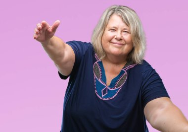 Kıdemli artı boyutu ile gülümseyerek kameraya bakarak arka plan üzerinde beyaz kadın izole silah sarılmak için açın. Neşeli ifade kucaklayan mutluluk.