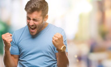 Soyutlanmış, mutlu ve heyecanlı genç bir adam kollarını kaldırmış, gülümseyen ve başarı için çığlık atan kazanan bir jest yapıyor. Kutlama konsepti.