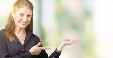 Güzel orta yaş olgun iş kadını üzerinden hayran ve el ile sunulması ve parmak ile işaret ederken kameraya gülümseyen izole arka plan.