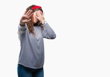 Güzel esmer kıvırcık saçlı Genç kız üzerinde çizgili süveter giyen izole elleriyle gözlerini kapsayan arka plan ve dur jest ile acı ve korku ifadesi. Utandım ve negatif kavramı.