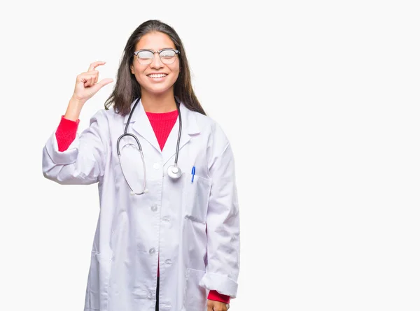 年轻的阿拉伯医生妇女在孤立背景微笑和自信手势与手做大小符号与手指 而看和相机 测量概念 — 图库照片