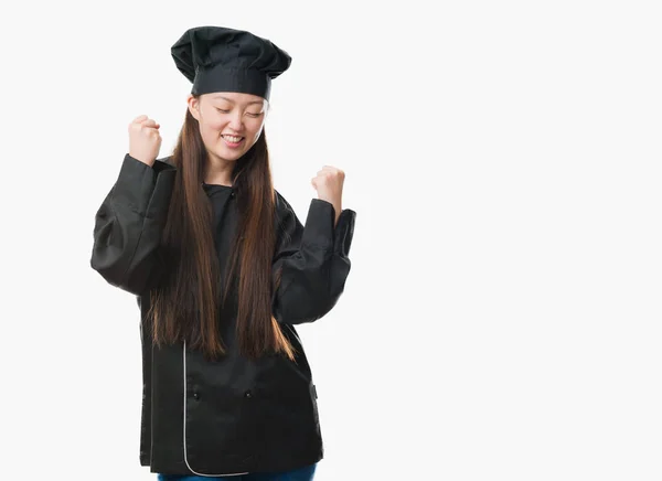 若い中国の女性非常に幸せと興奮の腕を上げ 勝者のジェスチャを行うシェフの制服を着て孤立の背景に笑みを浮かべて 成功のために叫んで お祝いのコンセプト — ストック写真