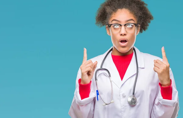 年轻的美国黑人医生妇女在孤立的背景下惊讶和惊讶地看着手指和举起手臂 — 图库照片