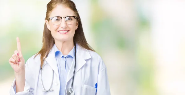 中年成熟的医生妇女穿着医疗外套在孤立的背景显示和手指第一 同时微笑着自信和快乐 — 图库照片