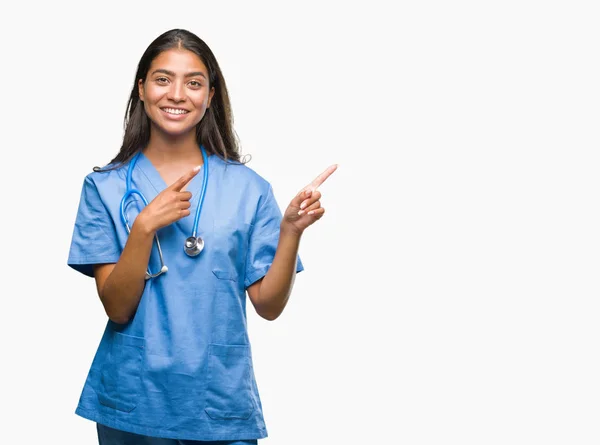 笑顔で側に つの手と指で指しているカメラを見て孤立の背景に若いアラブ医師外科医女 — ストック写真