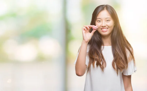 年轻的亚洲妇女吃粉红色的 Macaron 甜在孤立的背景下 一个快乐的脸站在微笑着自信的微笑显示牙齿 — 图库照片
