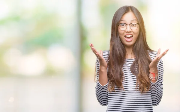 年轻的亚洲妇女戴着眼镜在孤立的背景下庆祝疯狂和惊讶的成功与手臂举起 睁开眼睛尖叫兴奋 赢家理念 — 图库照片