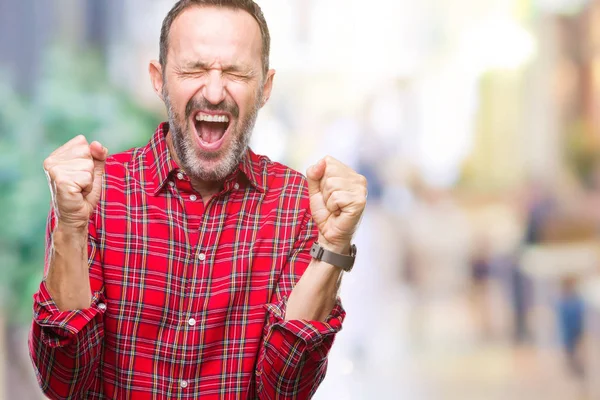 Orta yaş ağarmış üst düzey adam kızgın ve silah ile başarı için deli kutluyor izole arka plan üzerinde kaldırdı ve heyecanlı çığlık gözler kapalı. Kazanan kavramı